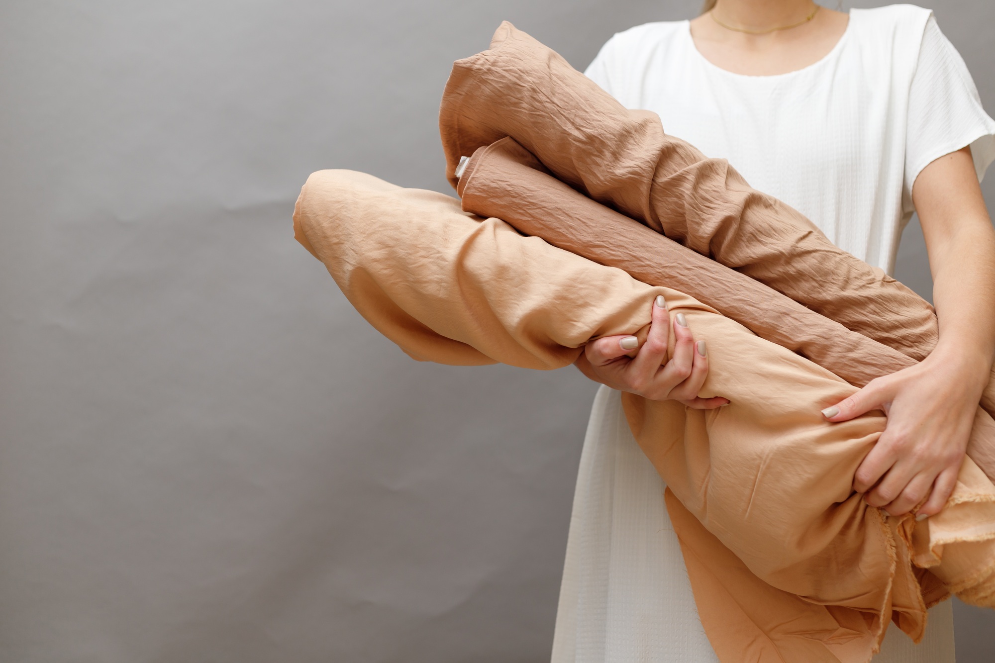 Business woman holding fabric rolls, working at textile shop.